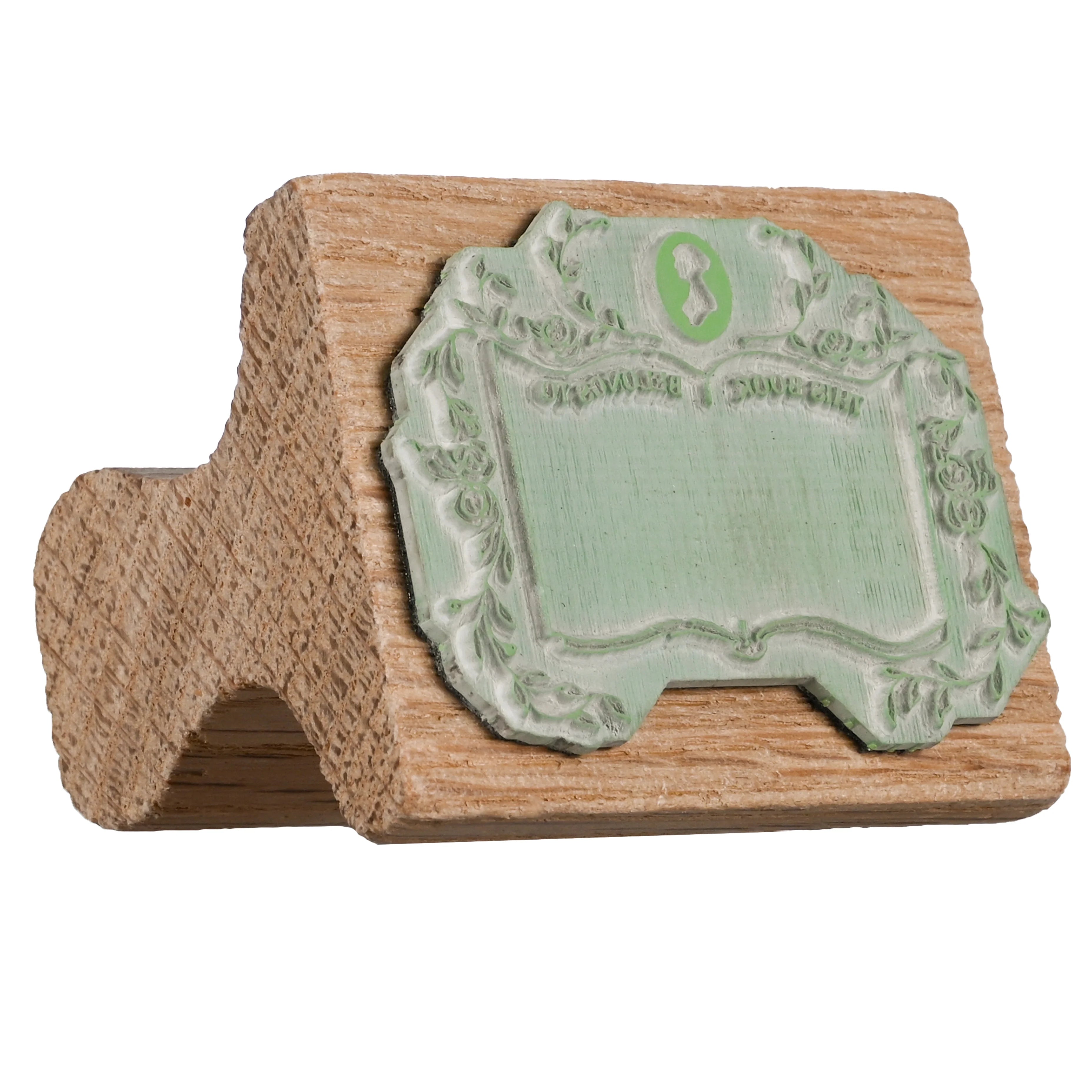 Wooden stamp with a Jane Austen logo, floral framing and backwards text  "This book belongs to"