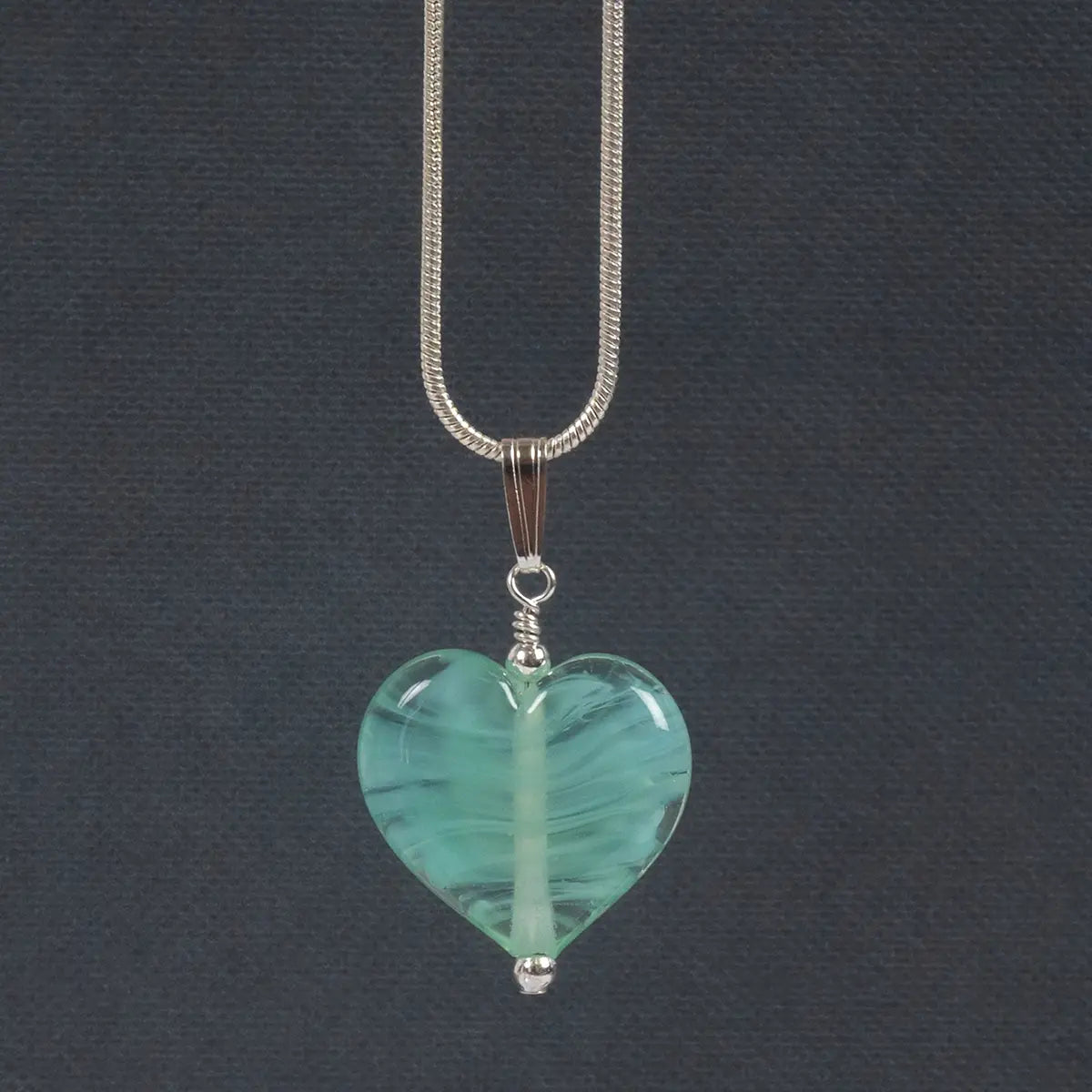 mint coloured glass hat on a silver chain against a dark grey background