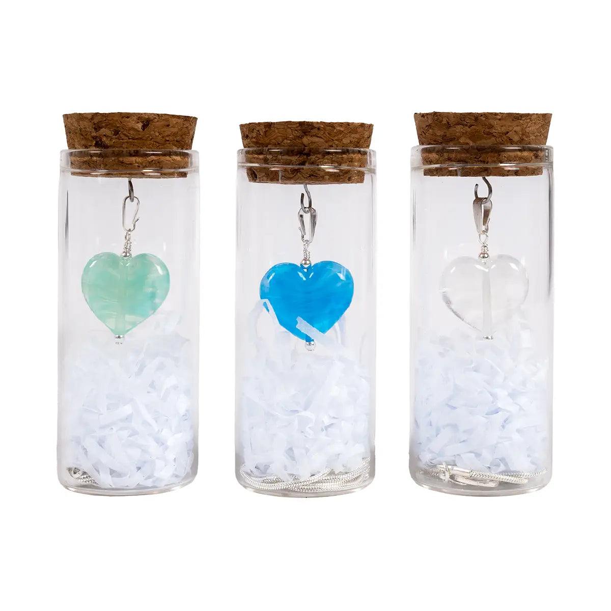 Necklace pendants in mint, blue, and white/clear glass, with chains and shredded tissue paper, in glass tubes with cork stoppers.