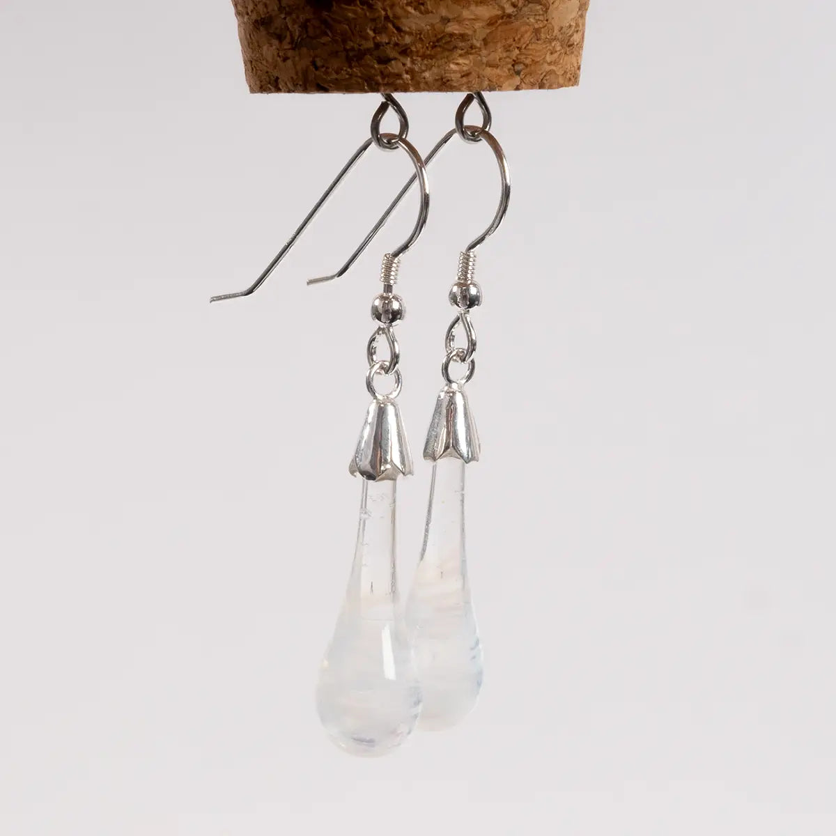 white glass drop earrings hanging from a cork with metal loops