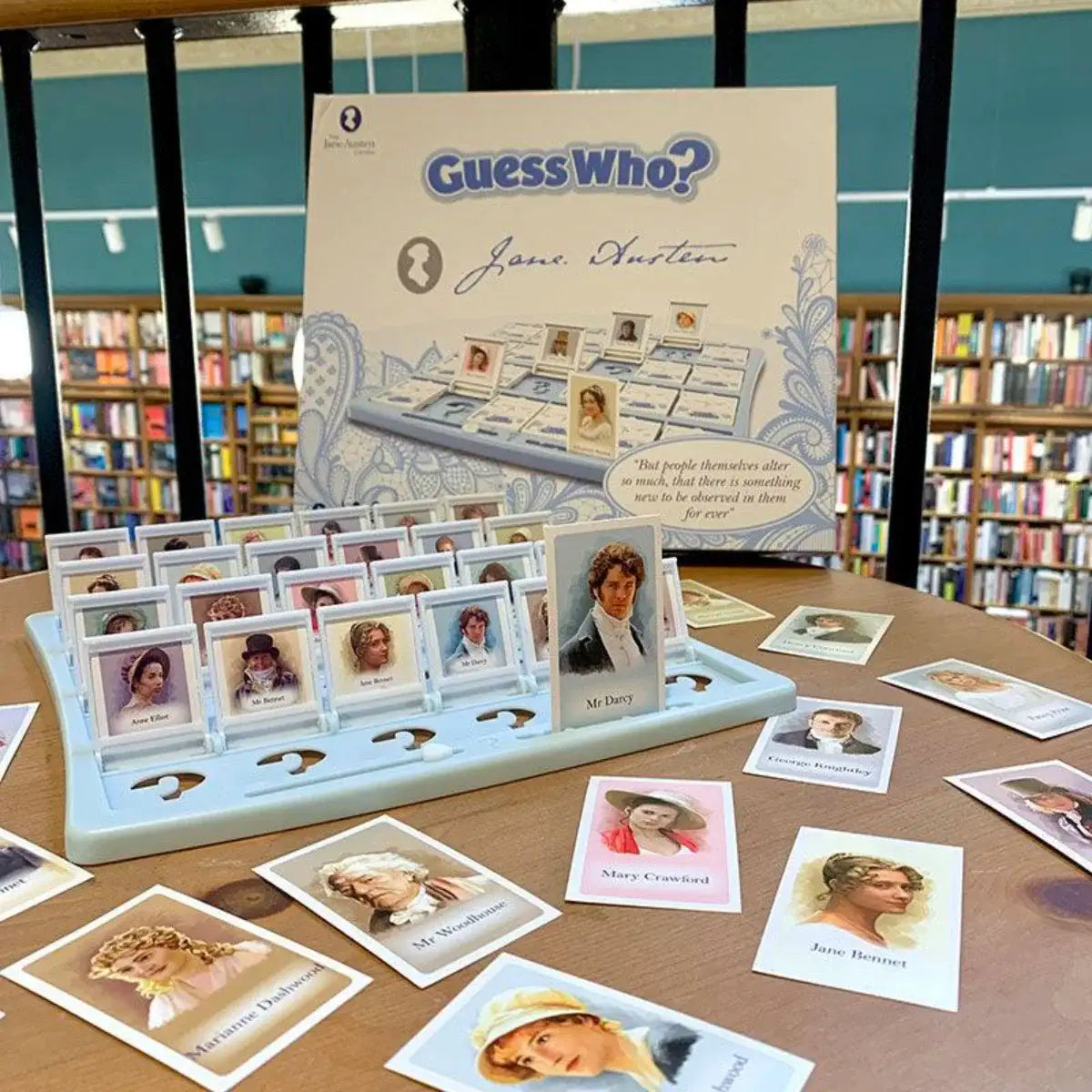 Jane Austen Guess Who and cards on a table in a room filled with books