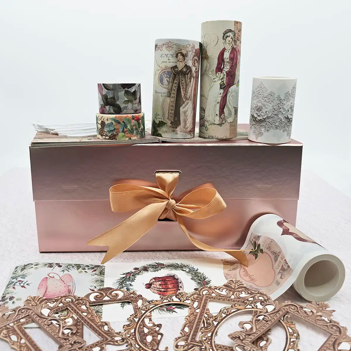 Decorative items including washi tapes, cut-out frames, and a box with a gold bow on a white background.