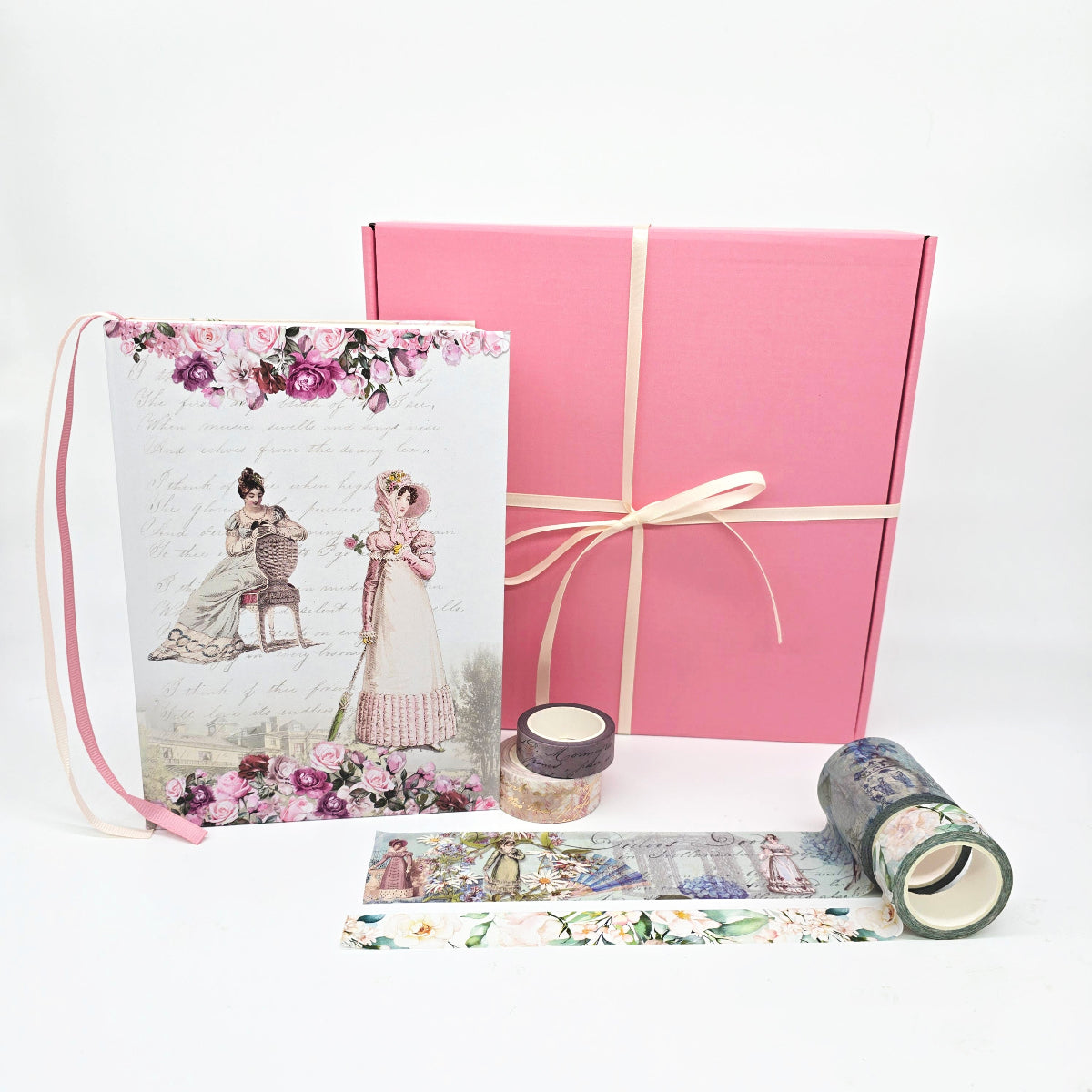 Set of stationery items including a pink gift box, floral-patterned journal and washi tape on a white background.