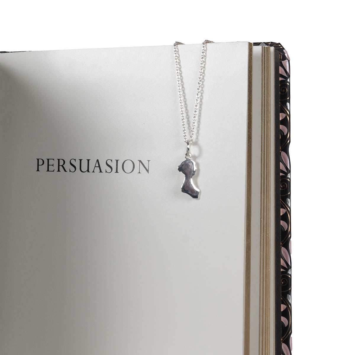 Jane Austen Silver Silhouette Pendant Necklace on silver chain hanging over a book