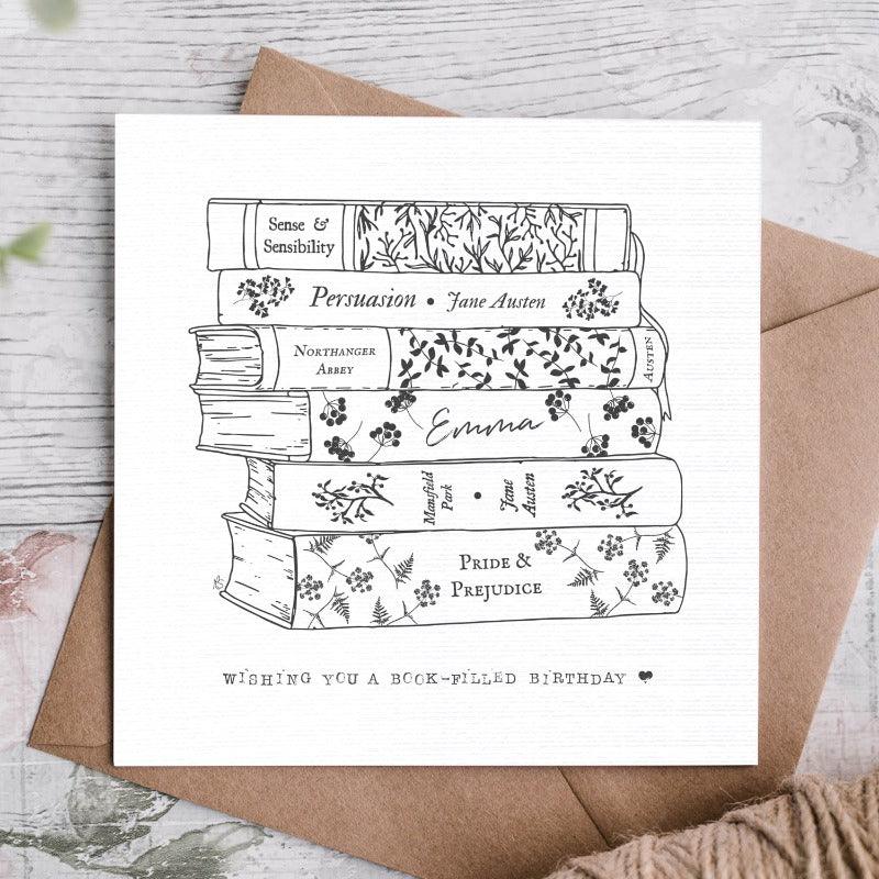 "Wishing you a book-filled birthday" Card - it shows the black and white line drawing of each book stacked on top of it eachother. The books are shown with flowery simple designs on them and each title is clear. 