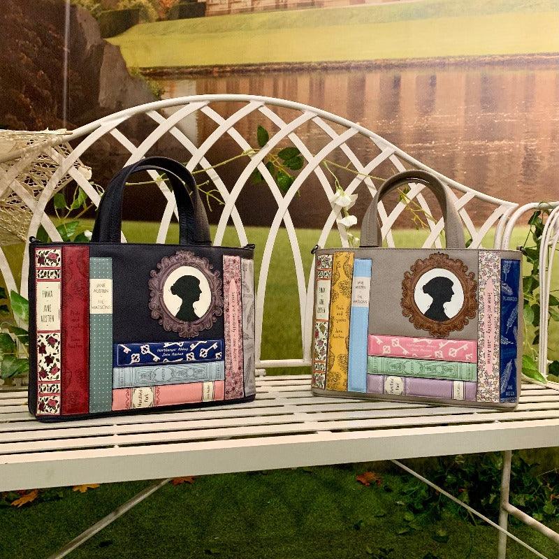 Two bags, navy and grey, sat on the a bench. Each decorated with Jane Austen books and silhouette